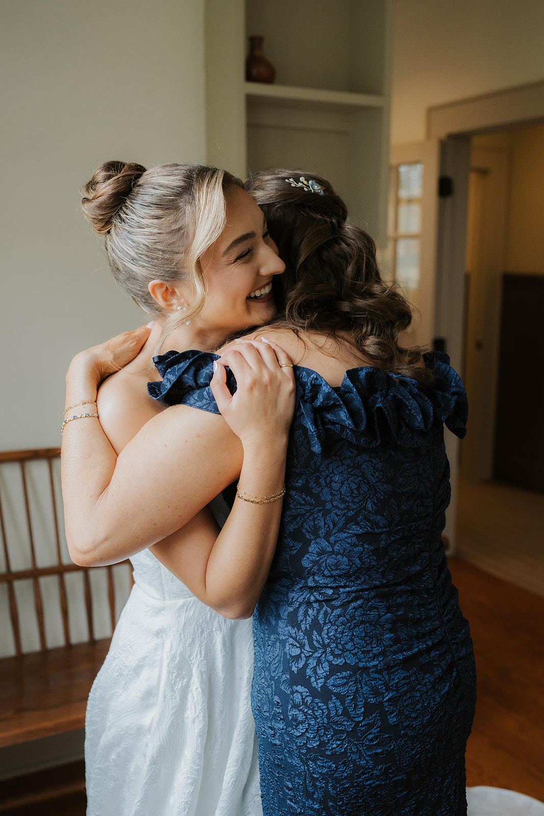 Color photo of the bride smiling and hugging her mother.