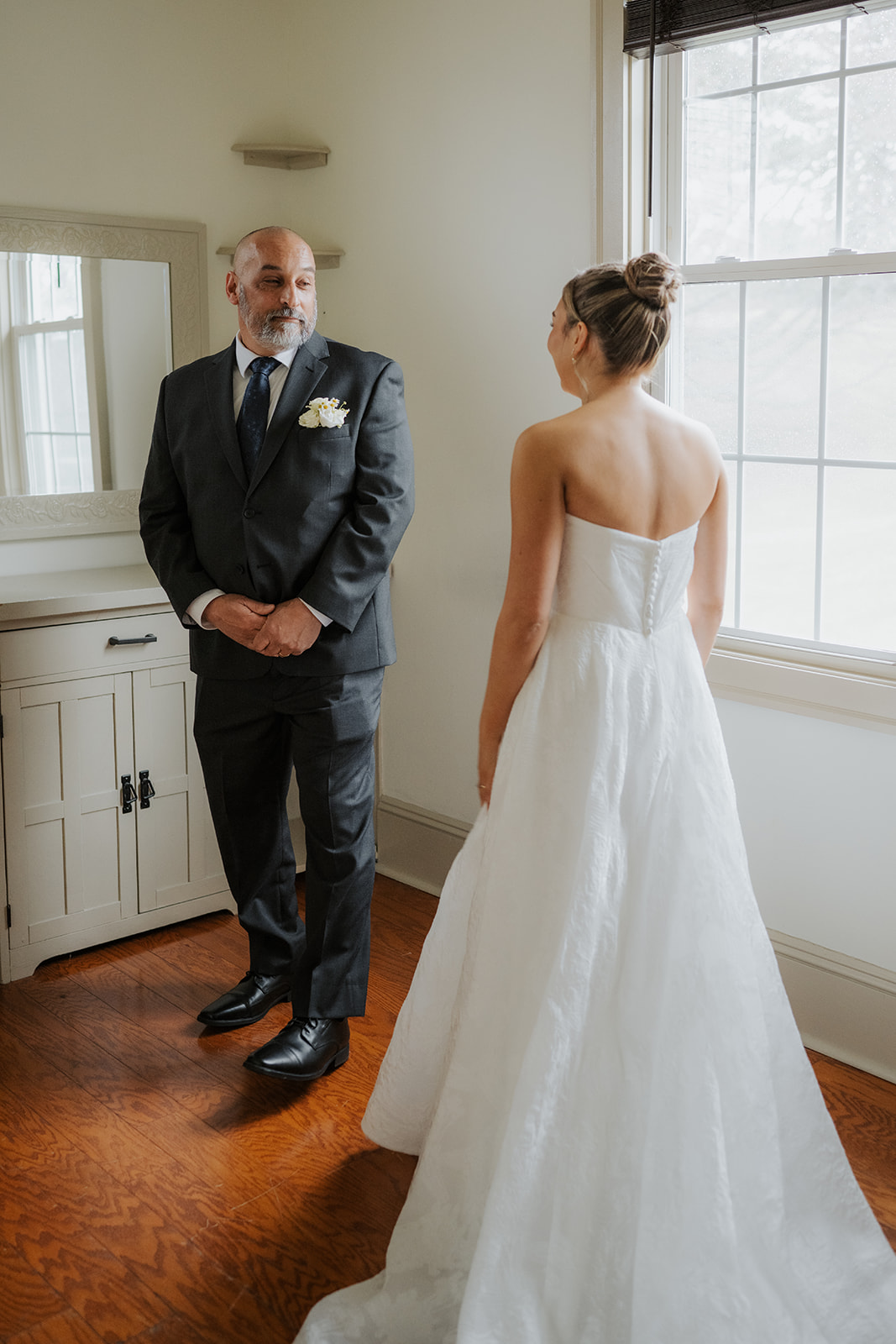 Father-daughter first look, standing in the suite, looking at each other.