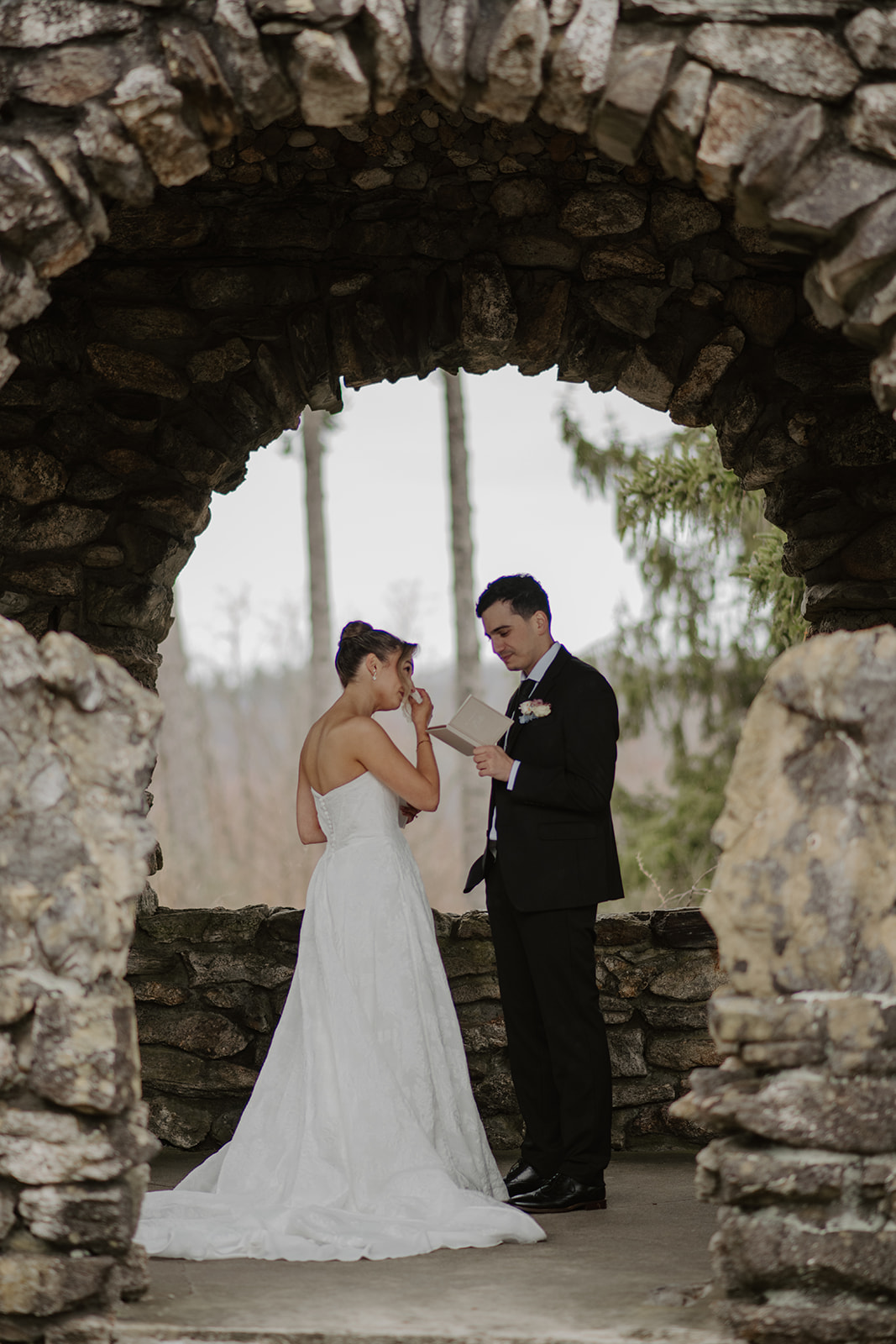 Groom reading private vows, while the bride wipes away a tear.
