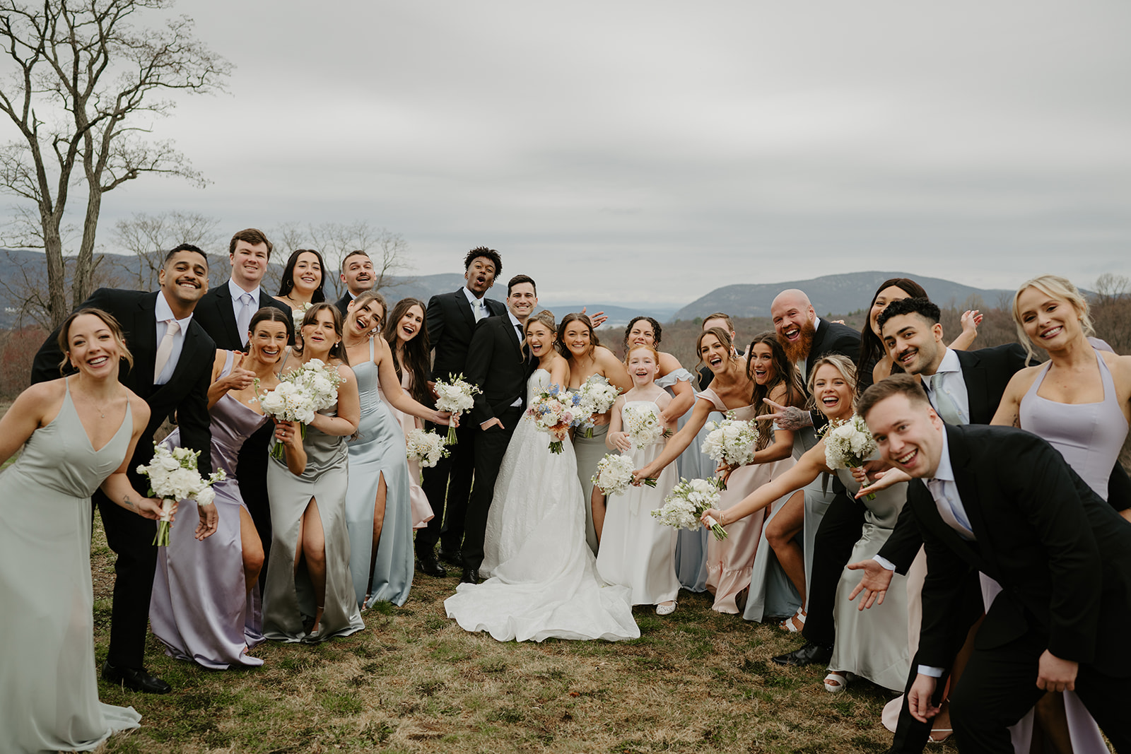 Wedding party being silly, leaning towards the camera and laughing.
