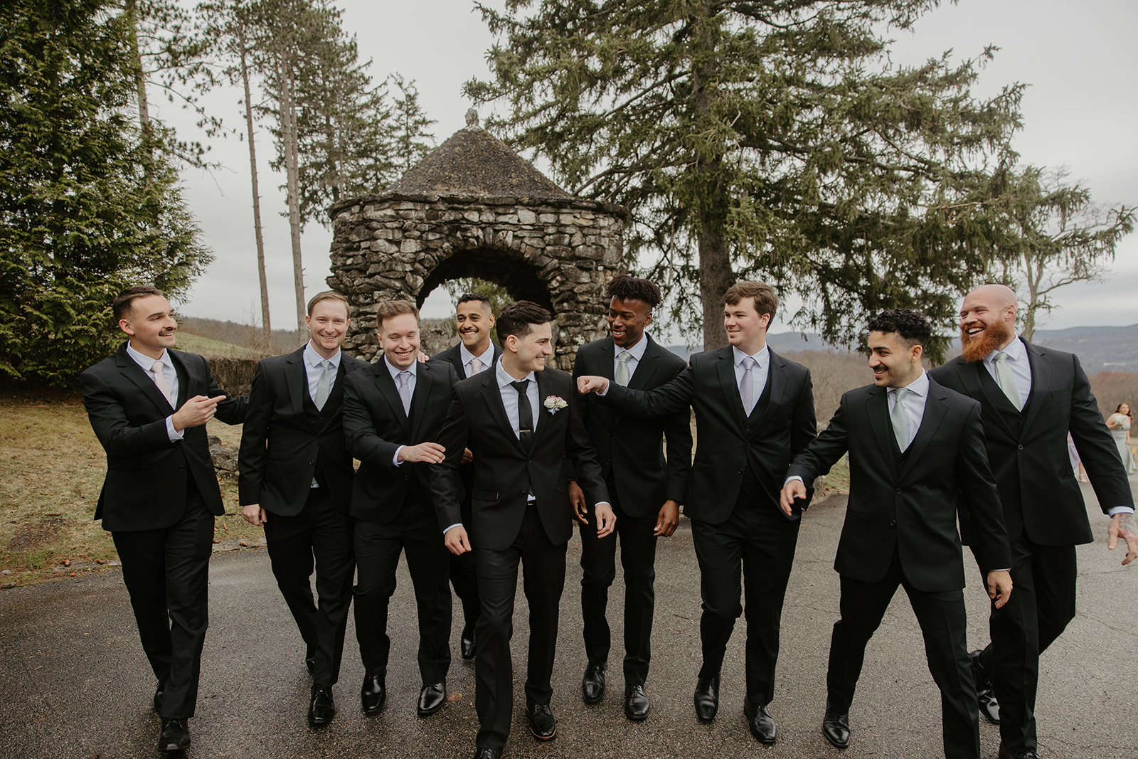 Groom walking and laughing with his groomsmen outside the stone gazebo.