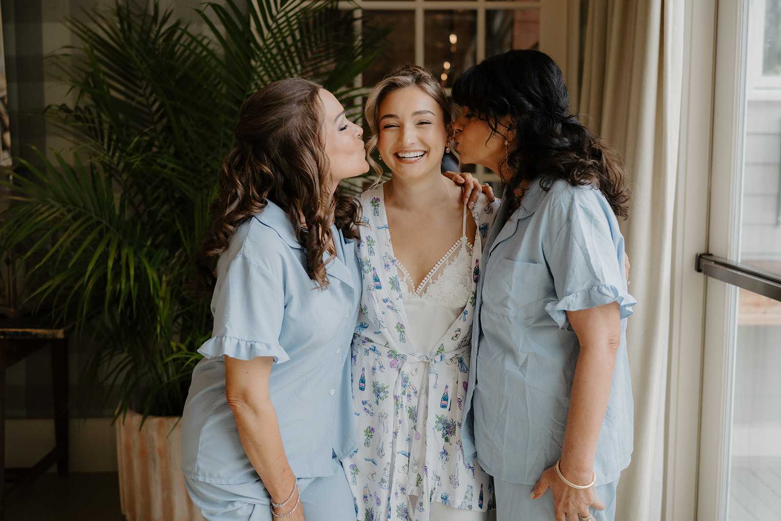 Bridesmaids kissing the bride on her cheeks in the bridal suite at The Garrison.