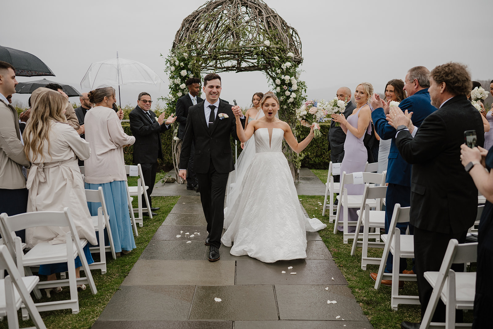 Recessional walk down the aisle, the couple smiling as guests applaud.