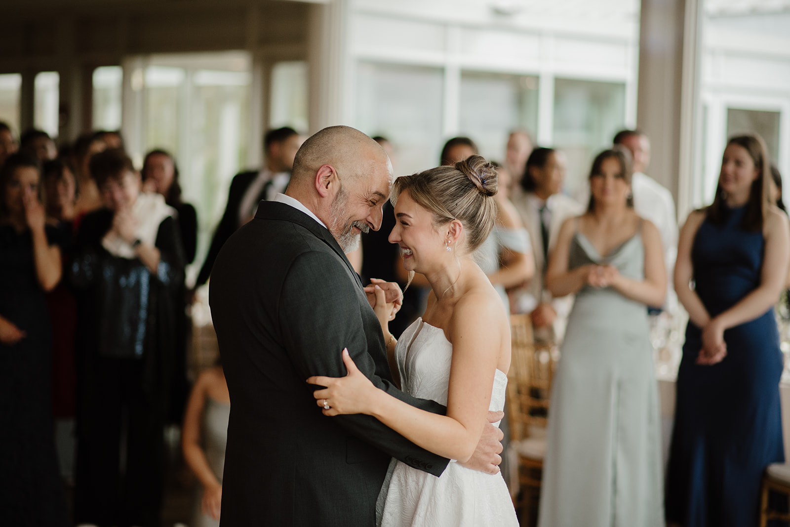 Bride and her father sharing an emotional dance during the reception, smiling warmly with heads close together.