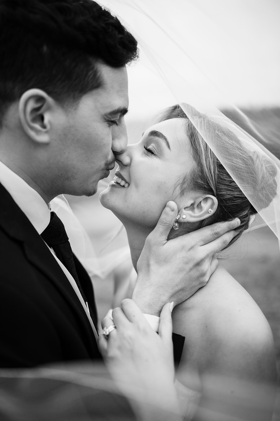 Intimate close-up black and white photo of the couple kissing under the bride's sheer wedding veil.
