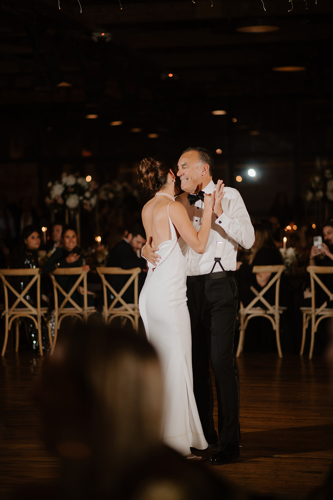 Bride dances with her father at the reception, both sharing a joyful smile.