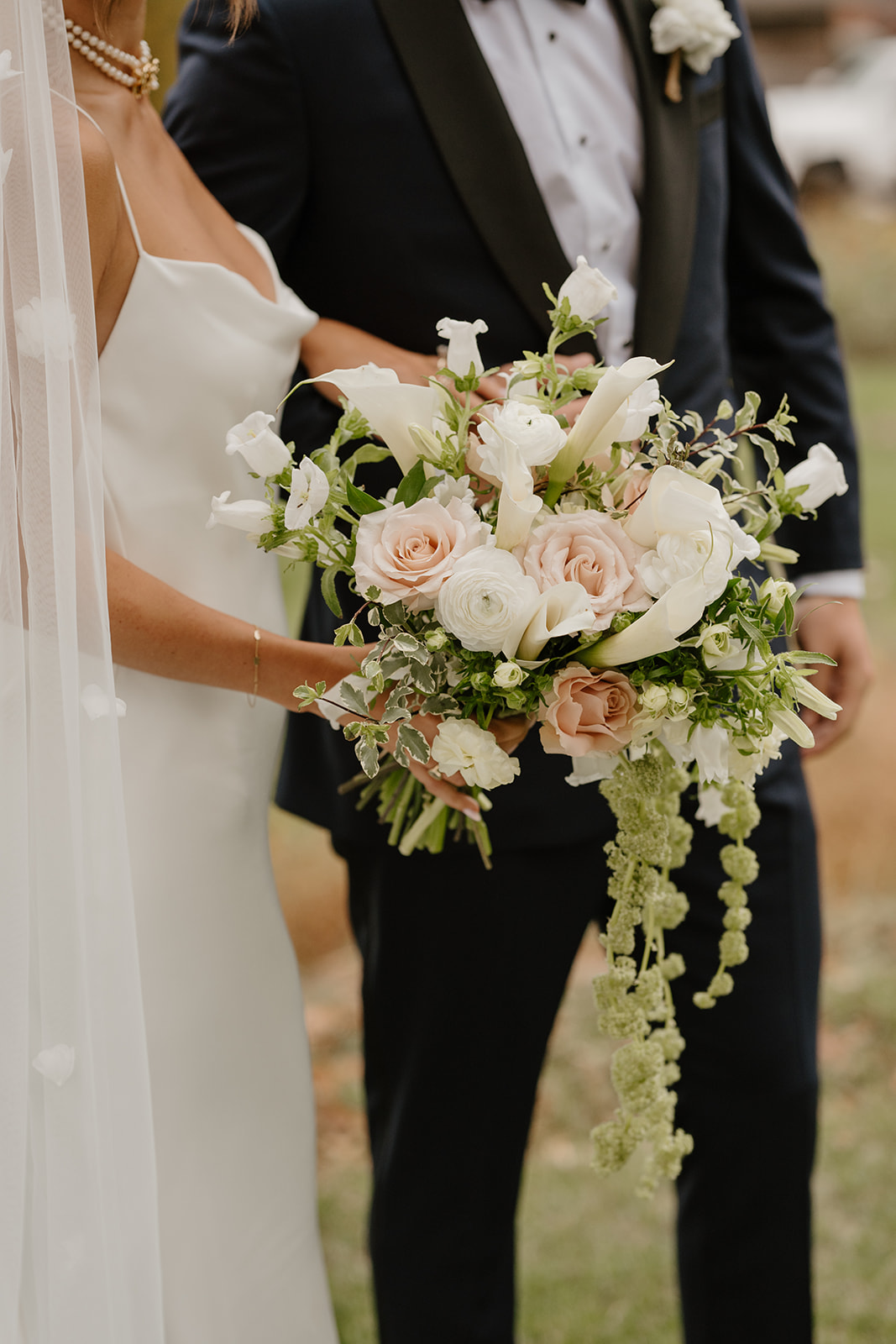 Close-up of the bride's elegant bouquet of blush roses, calla lilies, and cascading greenery.