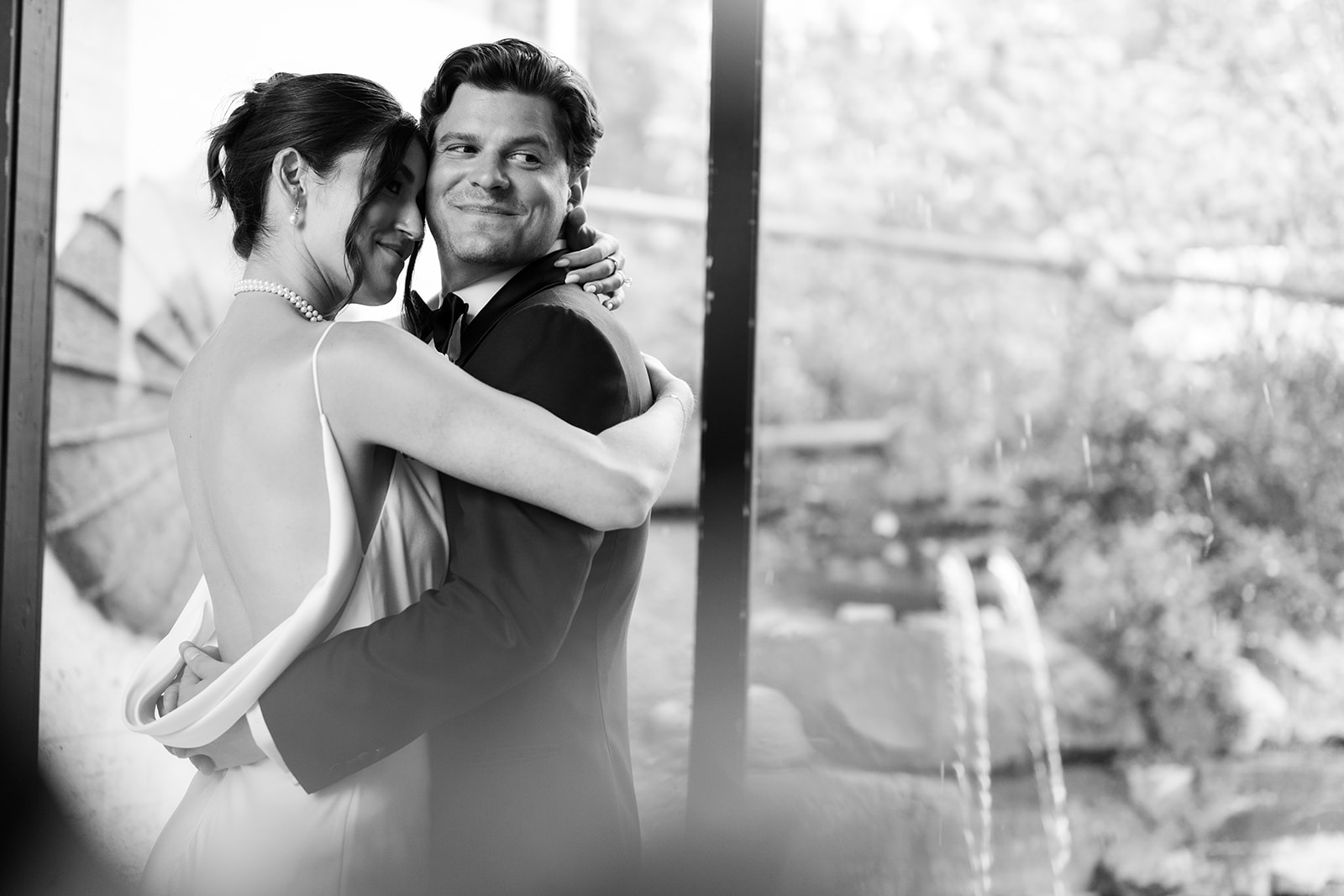 Black and white portrait of the couple embracing tenderly inside City Winery, looking out the window.