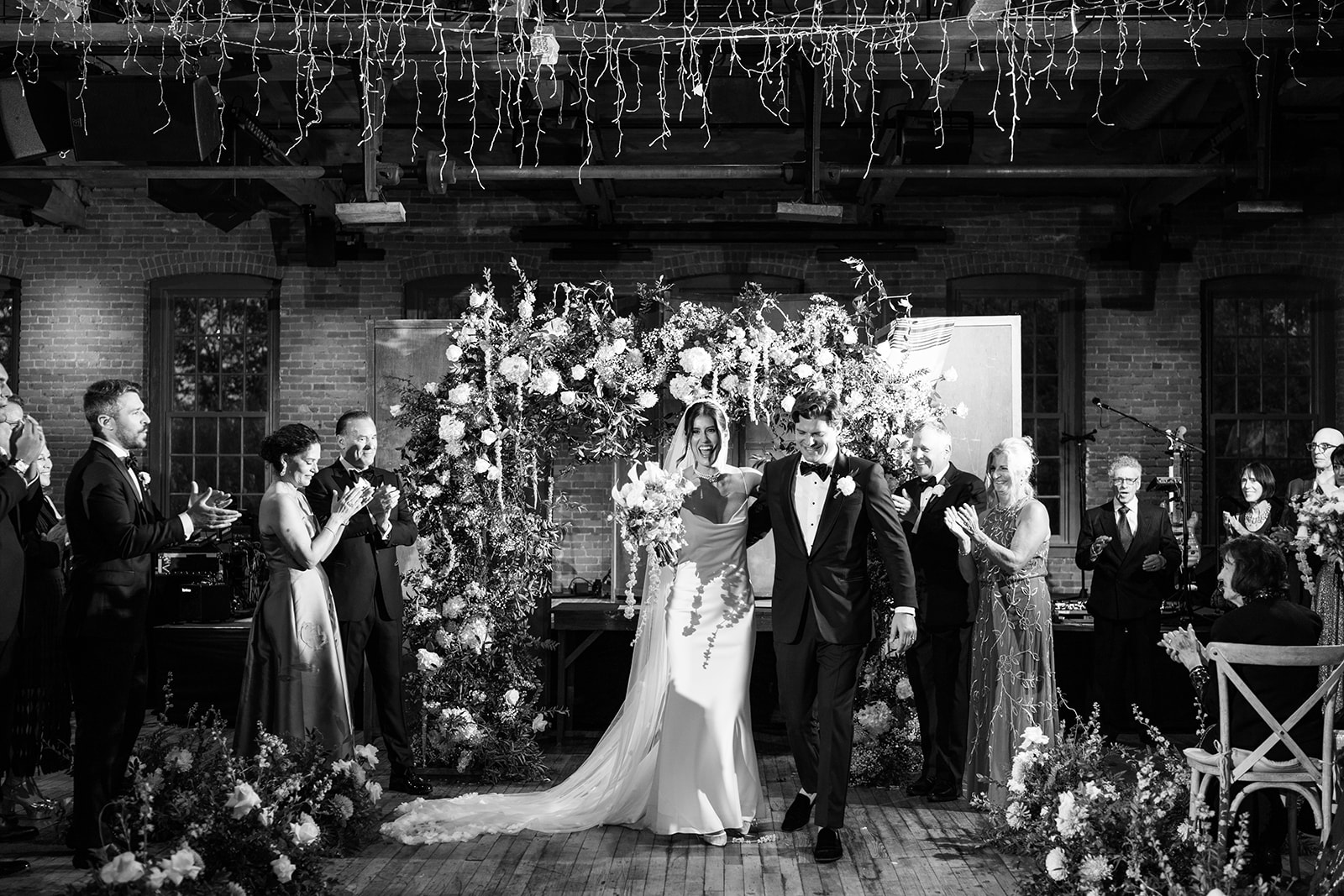 Black and white photo of the bride and groom walking down the aisle after their wedding ceremony.