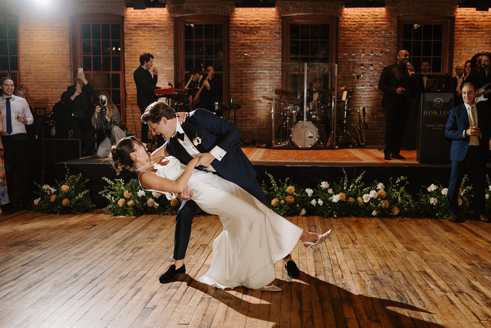 Groom dips the bride dramatically during their first dance as the live band performs behind them.